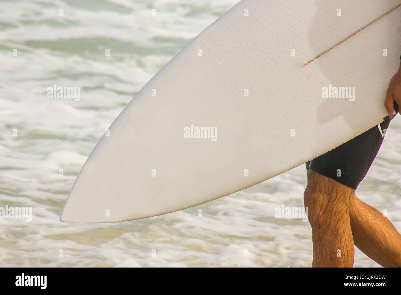 Surfer mit Surfbrett geht zum Meer am Strand Barra da Tijuca in Rio de Janeiro Brasilien. Stockfoto