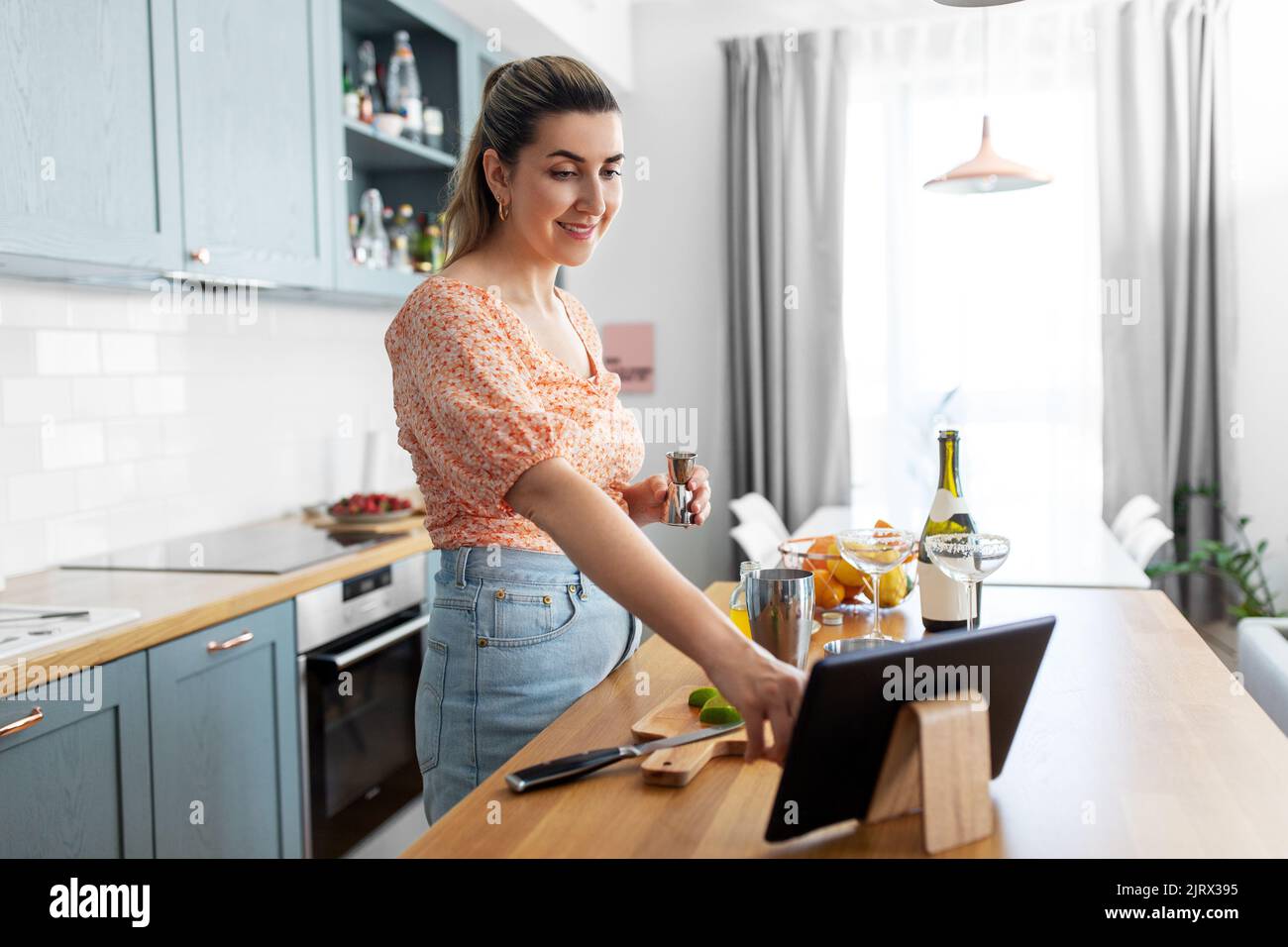 Frau mit Tablet-pc, die in der Küche Cocktails zubereitet Stockfoto