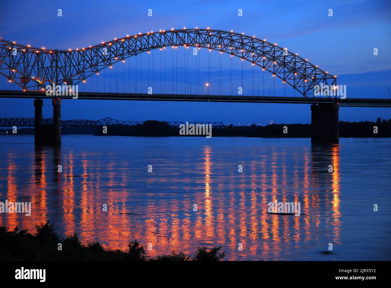 Die Lichter der DeSoto Bridge, die die I-40 zwischen Memphis Tennessee und Arkansas transportiert, spiegeln sich im ruhigen Wasser des Mississippi River wider Stockfoto