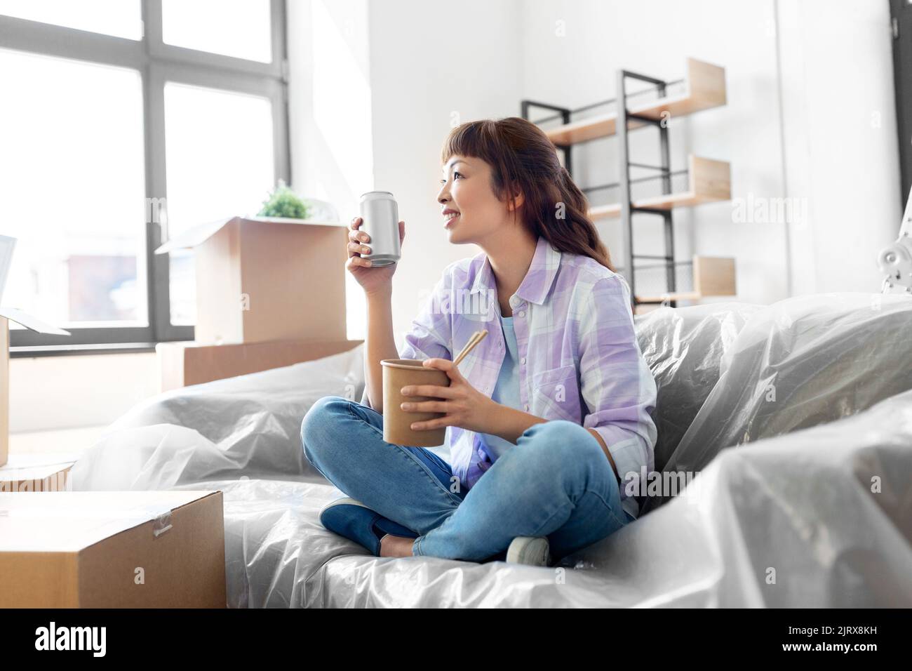 Glückliche Frau zieht in ein neues Zuhause und isst Wok Stockfoto