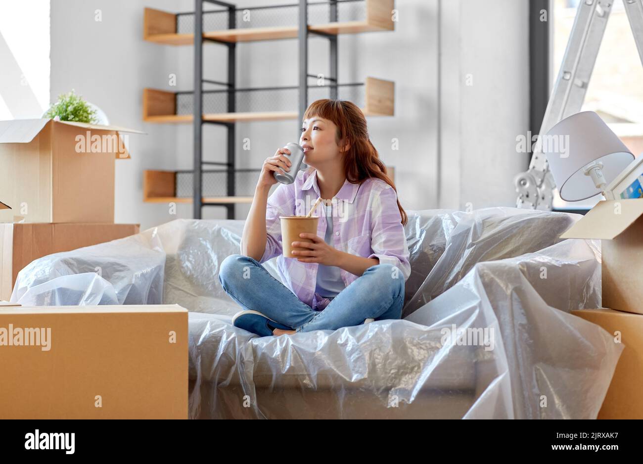 Glückliche Frau zieht in ein neues Zuhause und isst Wok Stockfoto