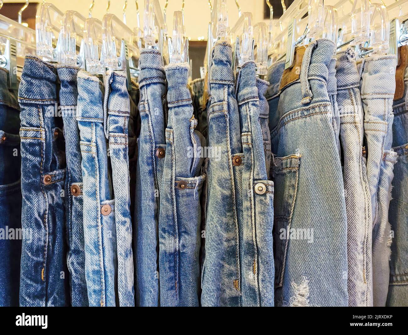 Eine Reihe von verblassten blauen Jeans hängt an einem Regal Stockfoto