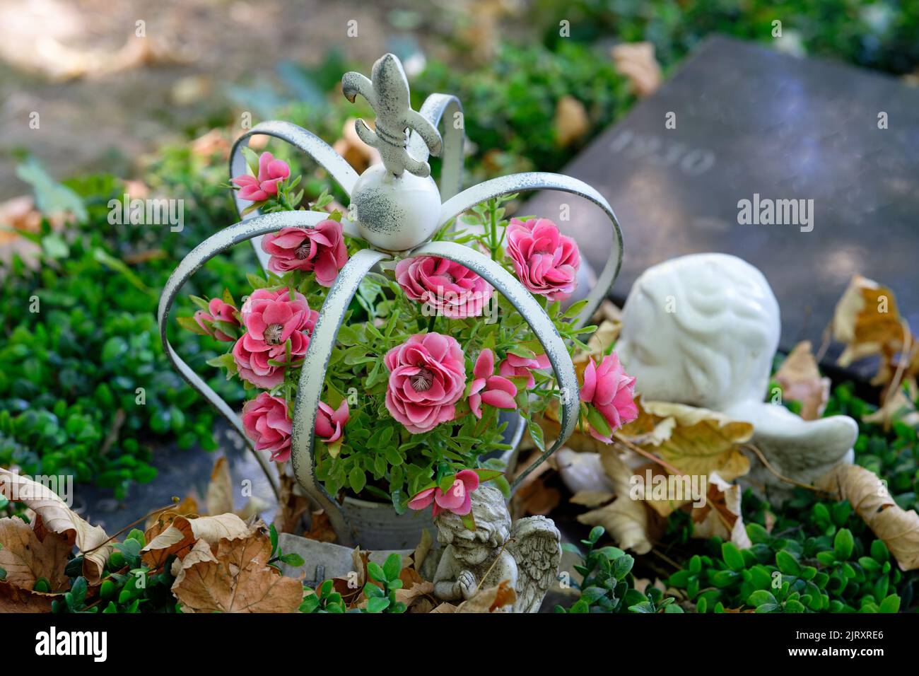 Blumen in einer Krone als Grabbeistellung auf einem Friedhof Stockfoto