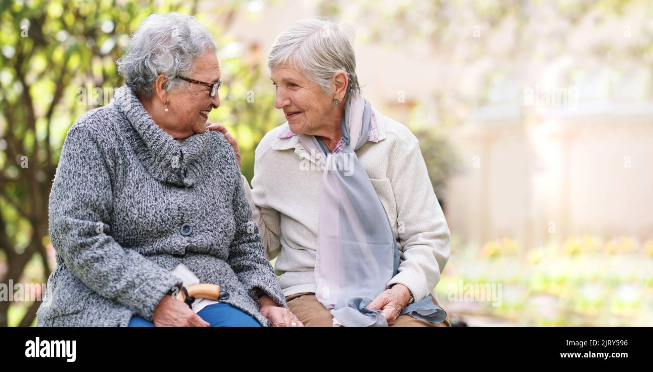 Zwei ältere Frauen sitzen auf der Bank im Park lächelnd glückliches Leben lang Freunde genießen Ruhestand Stockfoto