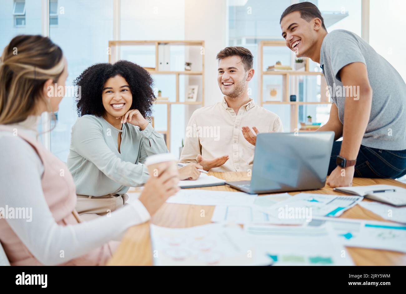 Glückliche Geschäftsleute, die lachen und sich in einem Büro unterhalten und eine Pause vom Papierkram einlegen. Vielfältige Arbeitsfreunde, die sich miteinander verbinden und darüber reden Stockfoto