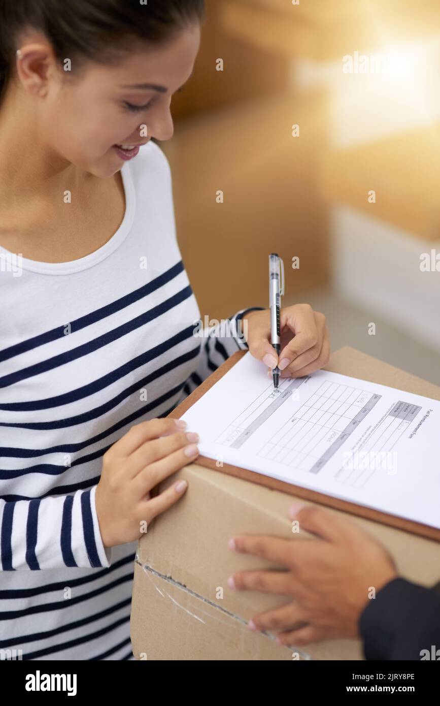 Ich liebe die Effizienz der Tür-zu-Tür-Lieferungen. Eine junge Frau, die ihr Paket vom Kurier unterschreibt. Stockfoto