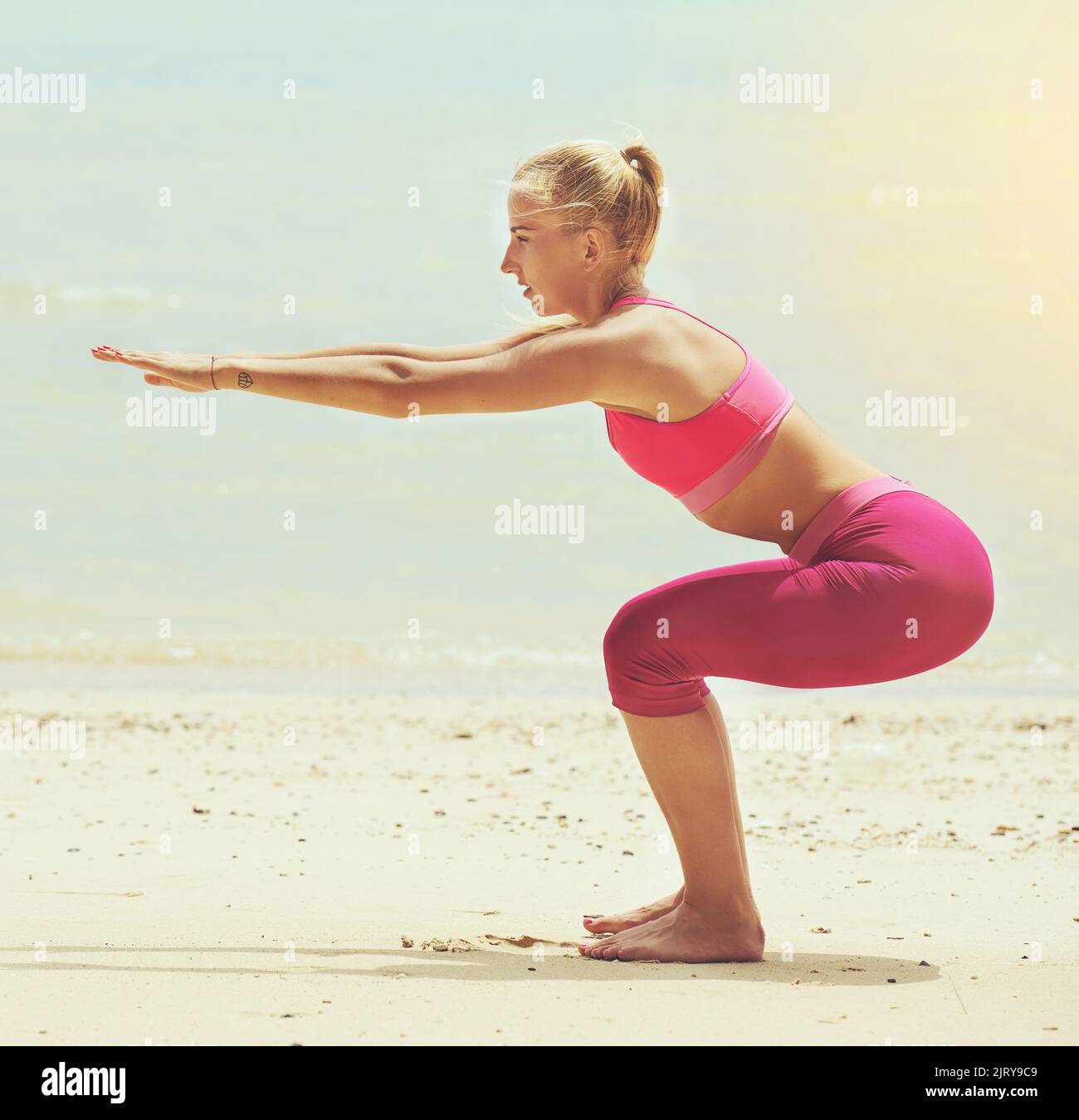 So werden Strandkörper gemacht. Eine fokussierte junge Frau, die am Strand Yoga macht. Stockfoto So werden Strandkörper gemacht. Eine fokussierte junge Frau, die am Strand Yoga macht. Stockfoto