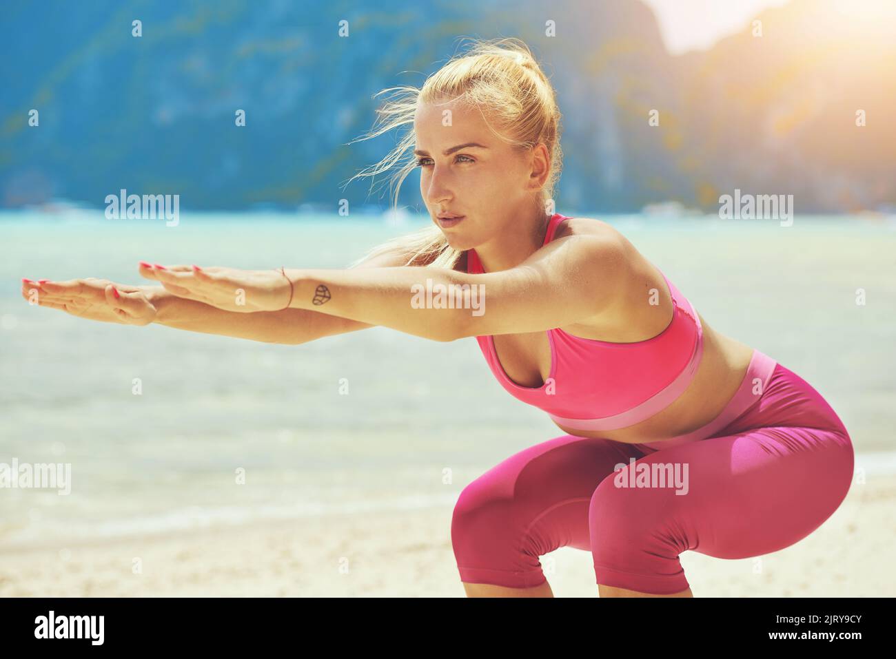 Greifen Sie nach Ihrem perfekten Körper. Eine fokussierte junge Frau, die Yoga am Strand macht. Stockfoto