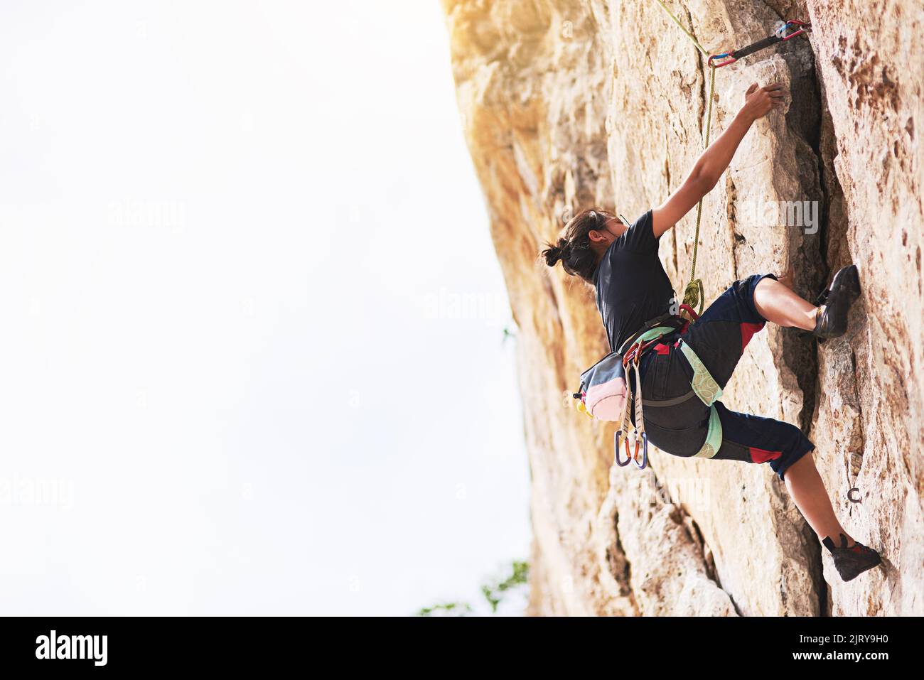 Halten Sie nicht an, bis Sie den Gipfel erreichen. Ein junger Kletterer, der eine Felswand bestieckt. Stockfoto