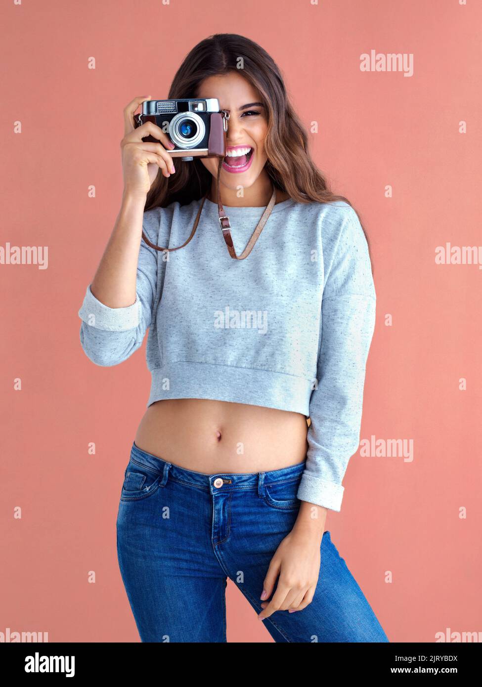 Ekstatisch, um Ihr Foto zu machen. Studioaufnahme einer schönen jungen Frau, die mit einer Vintage-Kamera vor einem rosa Hintergrund posiert. Stockfoto Ekstatisch, um Ihr Foto zu machen. Studioaufnahme einer schönen jungen Frau, die mit einer Vintage-Kamera vor einem rosa Hintergrund posiert. Stockfoto