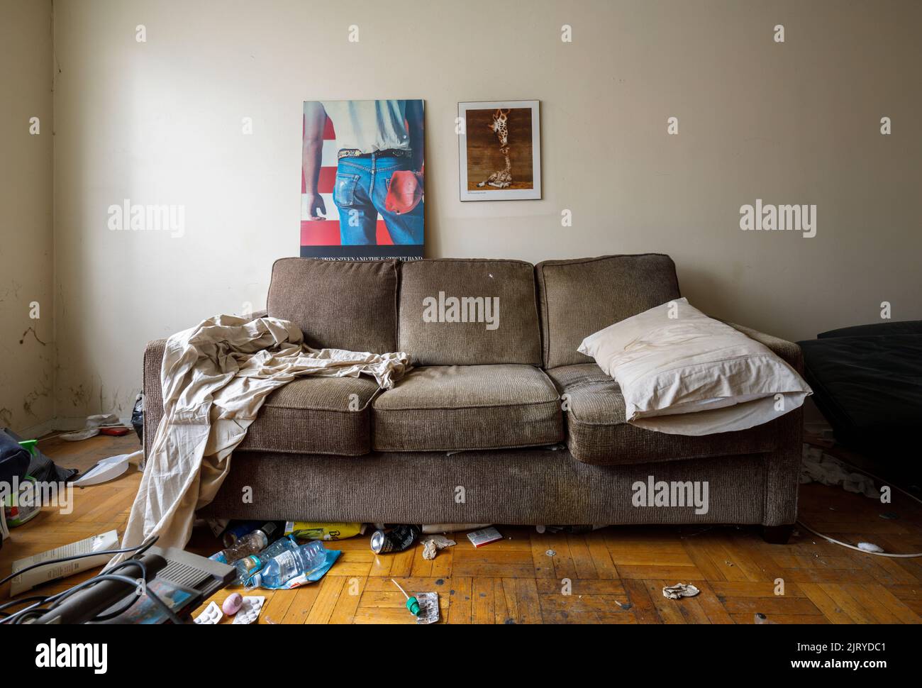 Eine Couch in einem schmutzigen Zimmer, die zum Schlafen eingerichtet ist. Dieses Gebäude wurde seitdem abgerissen. Stockfoto