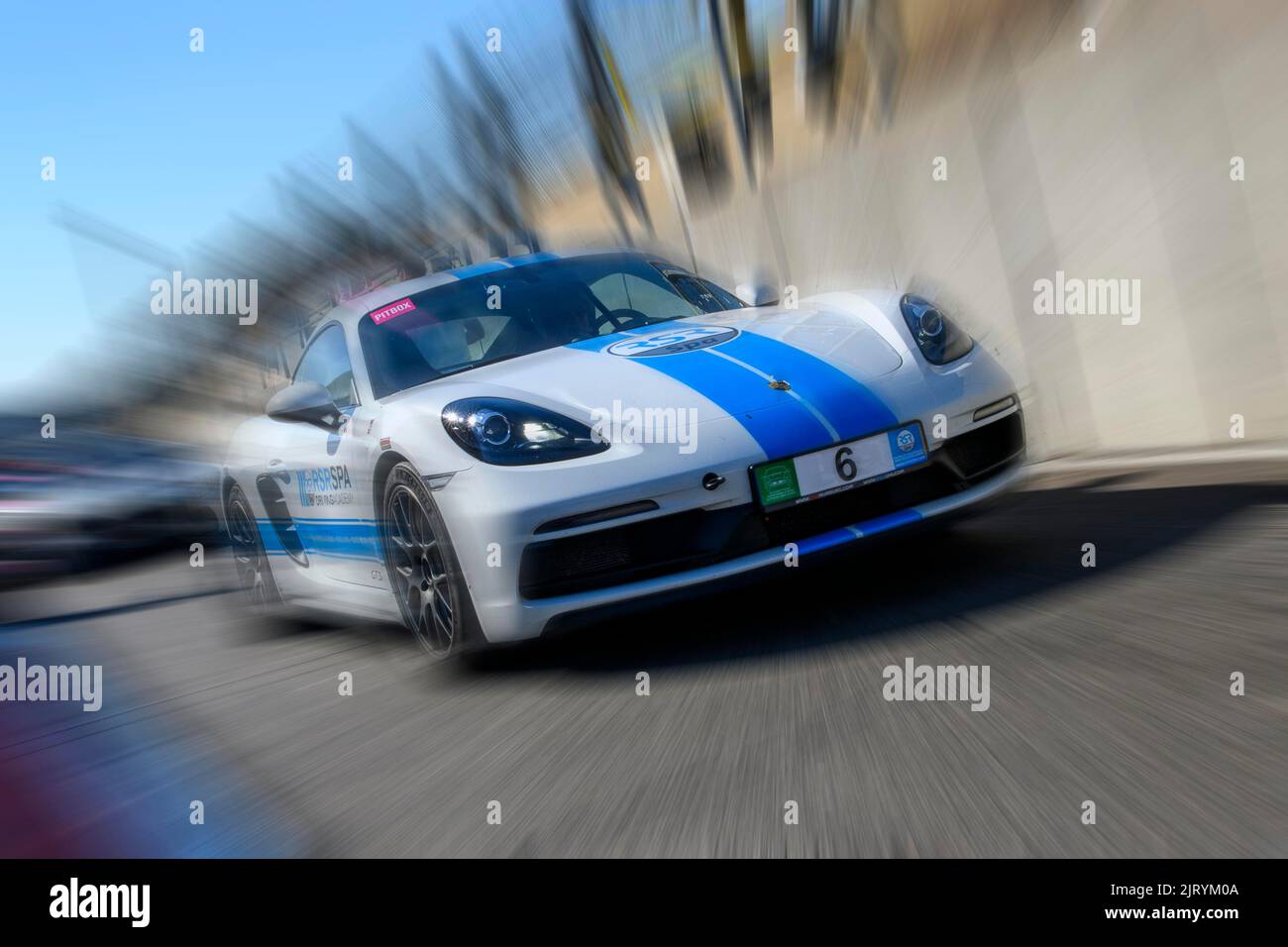 Dynamisches Foto mit Zoom-Effekt des Sportwagen-Rennwagens weiß mit blauem Streifen Porsche 718 Cayman GTS verlässt Boxengasse, FIA Formel 1 Strecke Stockfoto
