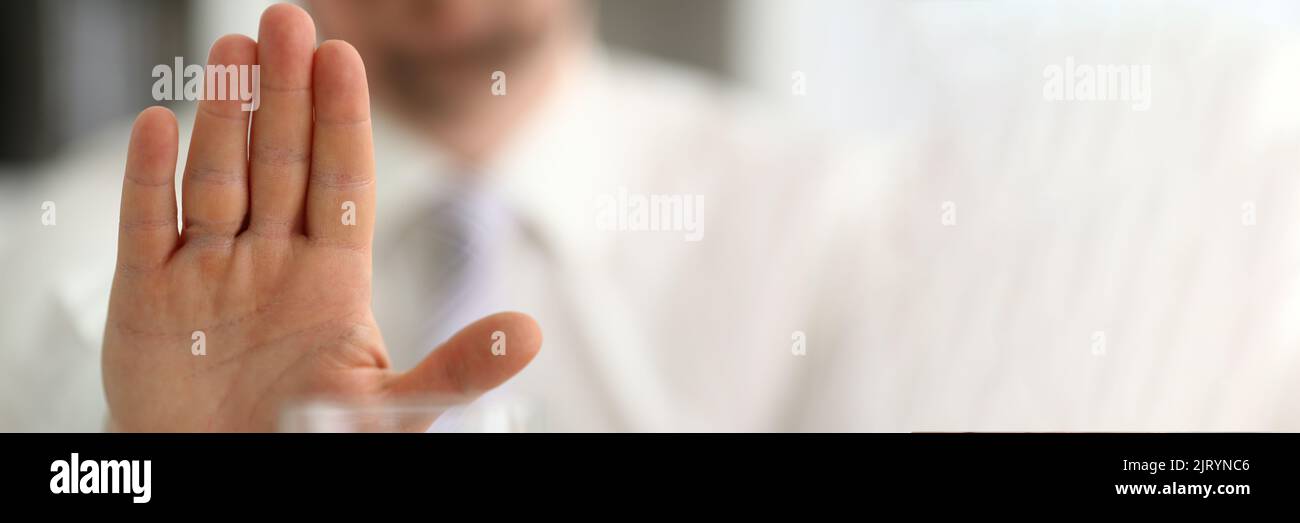 Männliche Hand zeigt eine negative Geste zum Glasbecher Stockfoto