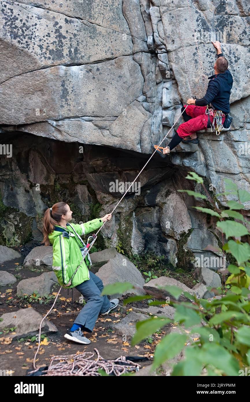 Ein Mann kletterte auf den Berg und eine Frau half ihm im Buky Canyon in der Nähe des Buky Dorfes im ukrainischen Cherkasy Oblast Stockfoto