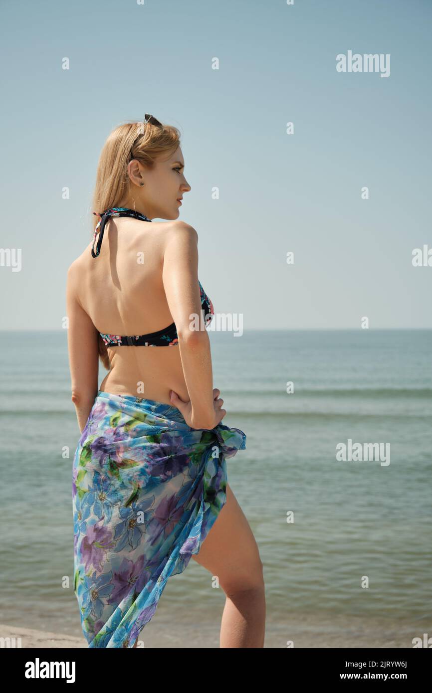 Alleinstehende junge blonde Frau im Badeanzug am Strand Sand, getöntes Bild Stockfoto