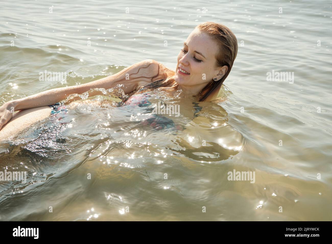 Junge blonde Frau im Badeanzug auf dem Meer surfen mit Schaum entspannen Stockfoto