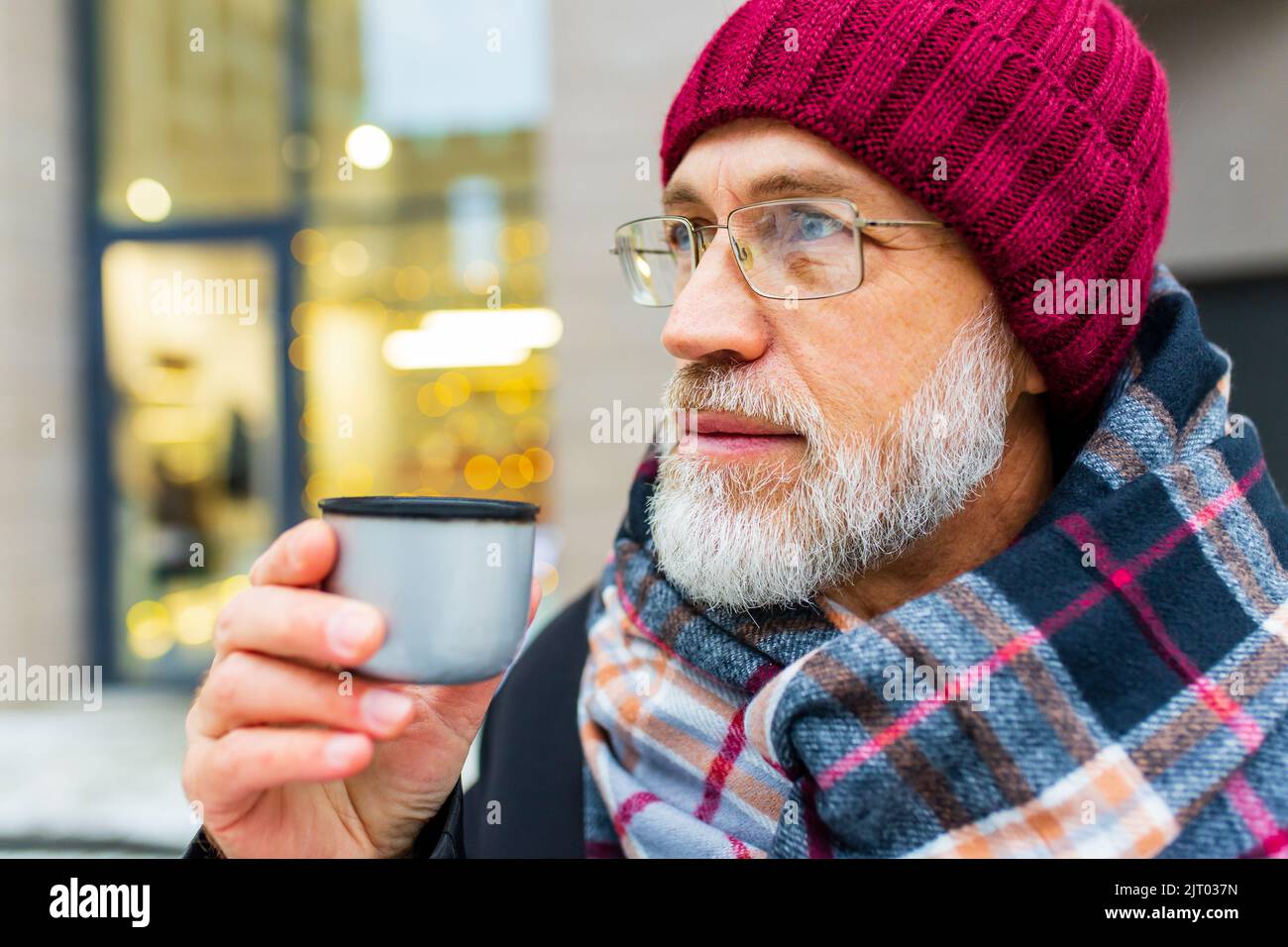 goog aussehender reifer Mann trinkt im Winter heißen Tee in der City Street Stockfoto