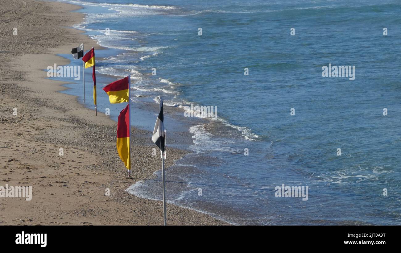 Rote und gelbe Strandfahnen, einschließlich schwarzer und weißer Flaggen an der Küste im Freien am Strand Stockfoto