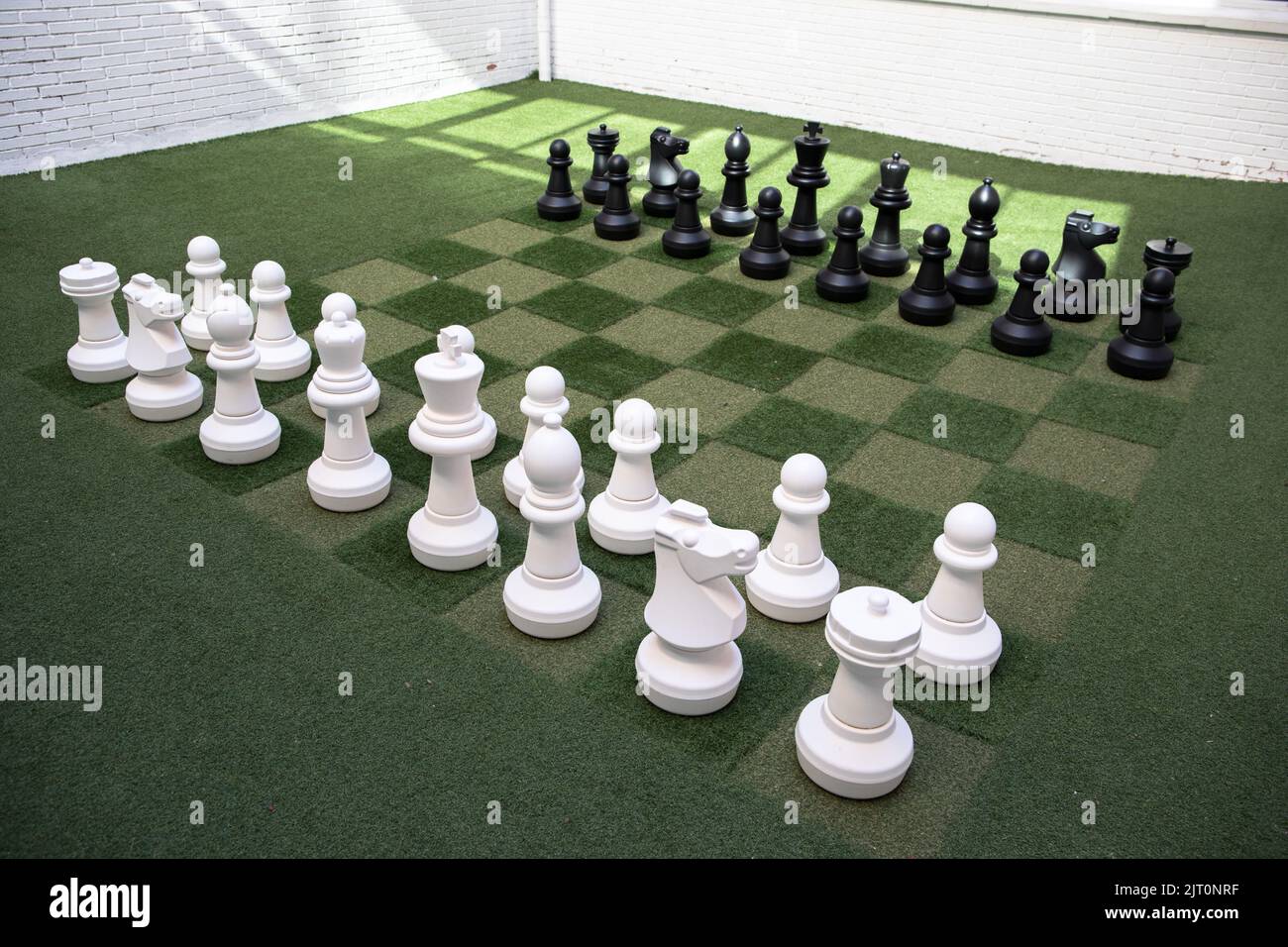 Eine hochwinkelige Aufnahme von Schach mit schwarzen und weißen Figuren auf einem Rasenbrett Stockfoto
