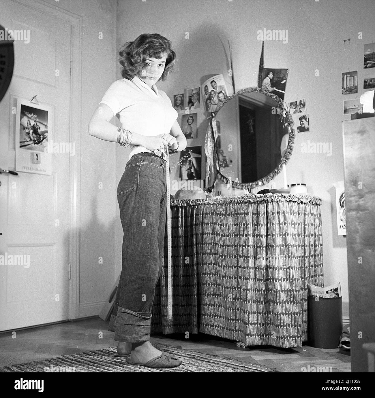 In der 1950s. Die Schauspielerin Harriet Andersson, geboren 1932, wurde bei der Messung ihrer Taille in ihrem Zuhause abgebildet. Sie trägt Jeans-Hosen.Schweden 1951 Conard Ref 1608 Stockfoto