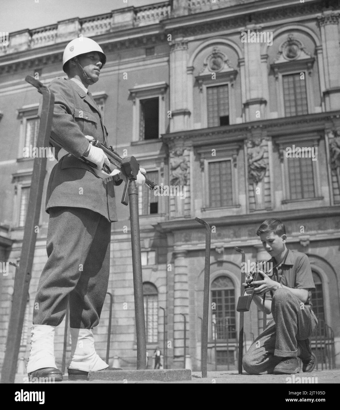 Fotograf im Jahr 1950s. Ein kleiner Junge mit seiner Kamera im Hof des königlichen Schlosses in Stockholm macht ein Bild des Burgwächters, der in Uniform und Waffe steht. Schweden 1951 Conard Ref. 2443 Stockfoto