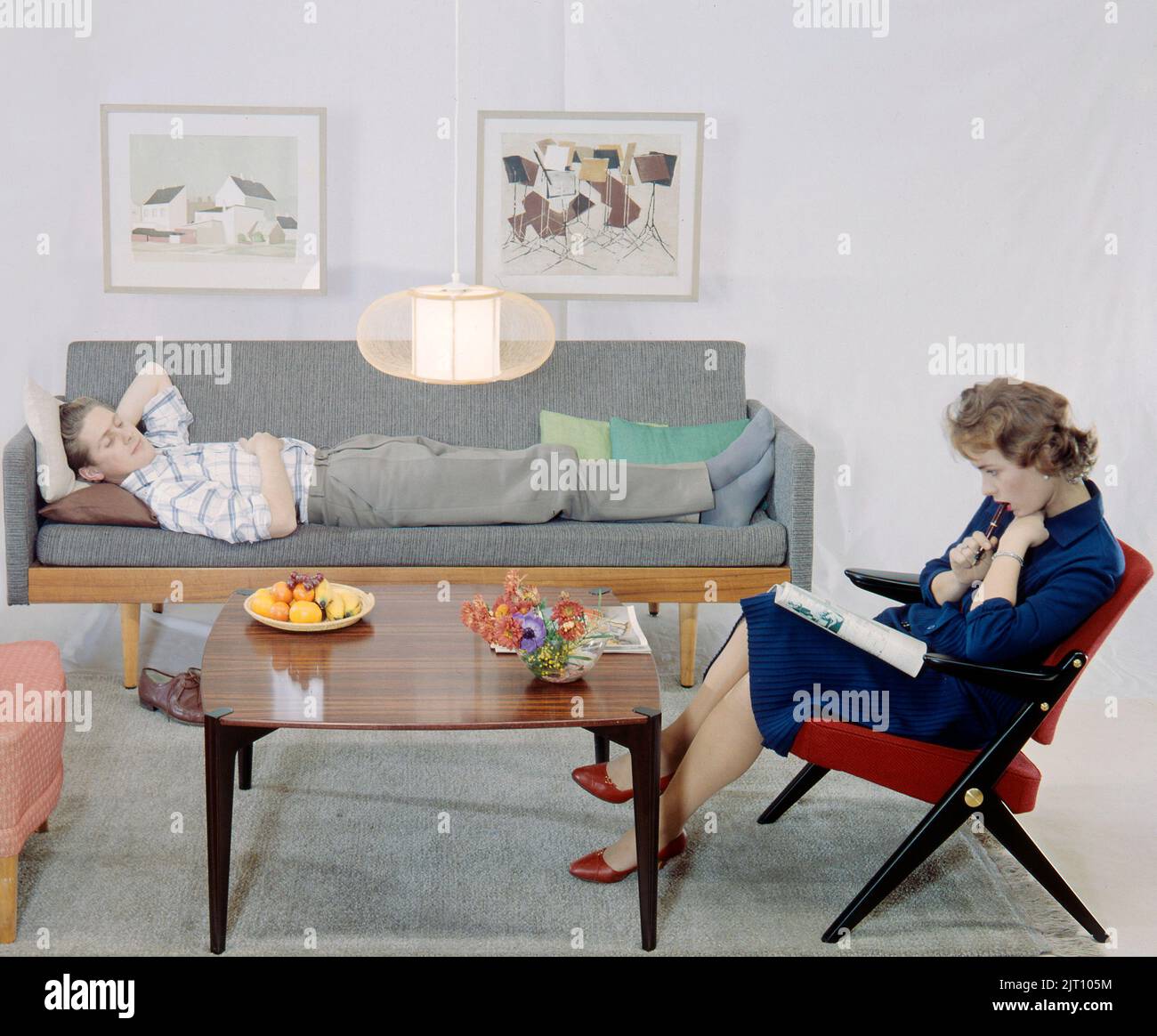 In der 1950s 1960s. Ein Mann und eine Frau in einem Zimmer mit Couch und Sessel. Die Möbel sind aus Holz und typisch für den späten 1950s frühen 1960s Stil. Schweden 1958 Conard Ref. BV50-1 Stockfoto