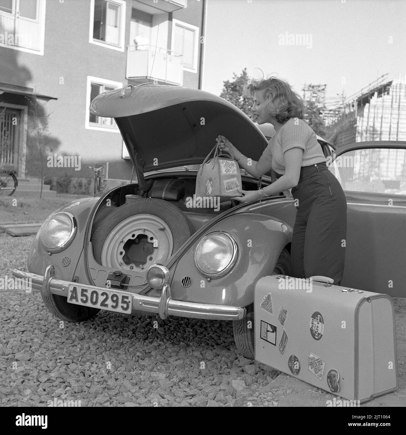 Fahren in der 1950er. Die Sängerin Bibi Johns macht eine Autofahrt und packt ihr Gepäck in den Kofferraum ihres VW-Autos. Beachten Sie, dass sich der Motor des Fahrzeugs hinten im Fahrzeug befindet und vorn Platz für Gepäck und Reserverad vorhanden ist. Schweden 1951 Conard 1724 Stockfoto