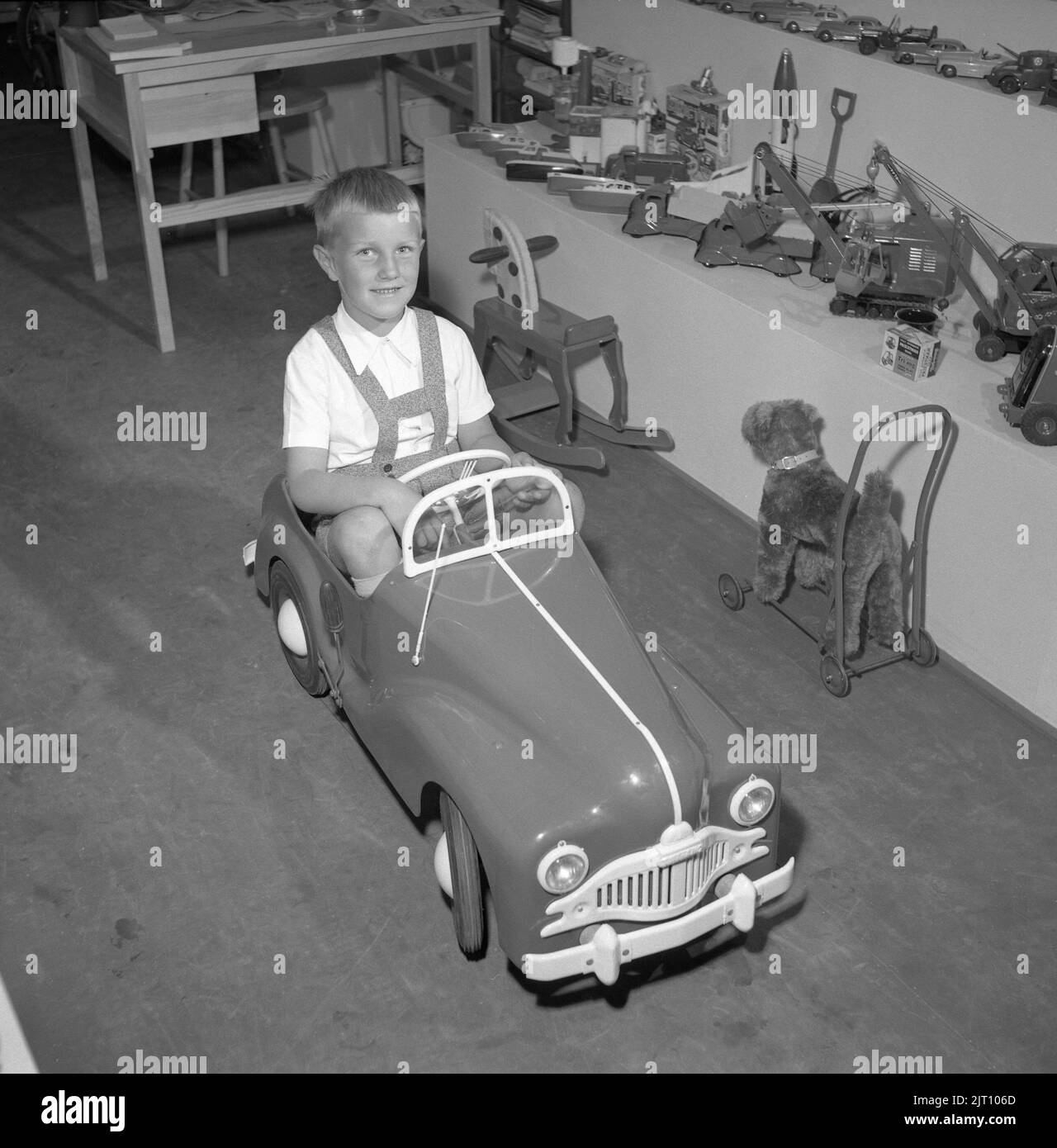 Junge in den 1950s. Auf der jährlichen Messe in Stockholm hat ein Stand mit Kinderspielzeug seine Ausstellung der neuesten verfügbaren Spielzeuge auf dem Markt. Der Junge probiert den Tretwagen aus und sieht glücklich aus. Schweden 1952 Conard Ref. 2112 Stockfoto