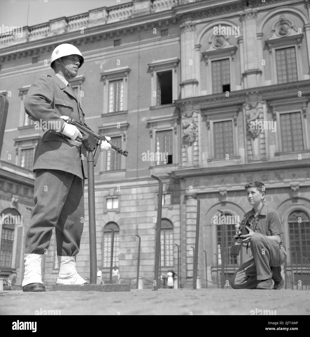 Fotograf im Jahr 1950s. Ein kleiner Junge mit seiner Kamera im Hof des königlichen Schlosses in Stockholm macht ein Bild des Burgwächters, der in Uniform und Waffe steht. Schweden 1951 Conard Ref. 2443 Stockfoto