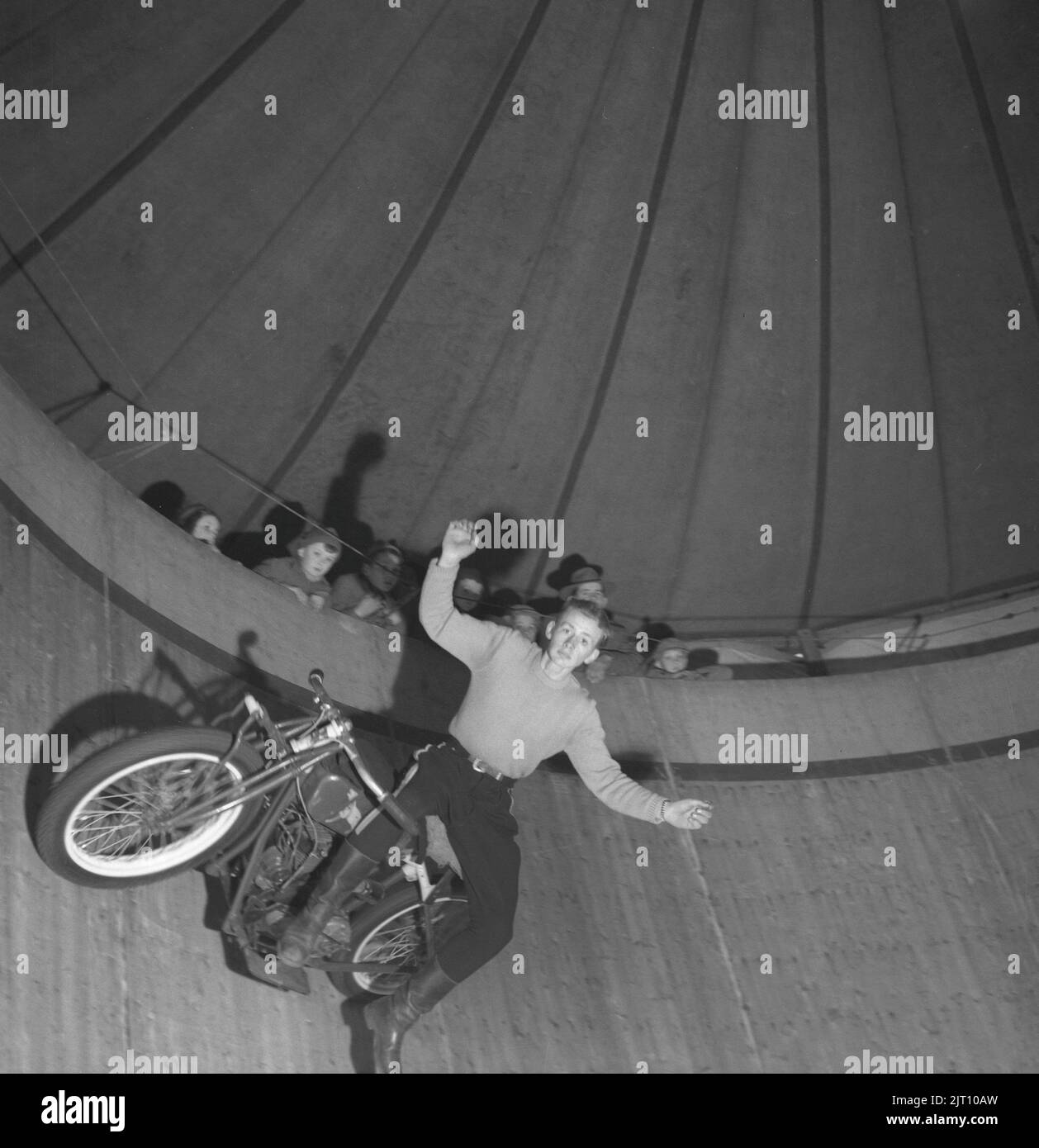 Motorradfahrer in der 1940s. A Ein junger Mann auf seinem Motorrad während einer Show in der Wall of Death (manchmal bekannt als Wall of Death, Motordrome, Silodrome. Wall of Death ist eine holzbeplankte tonnenförmige Arena, in der Zuschauer von oben beobachten, wie Motorräder oder andere motorisierte Fahrzeuge mit hoher Geschwindigkeit um sie herum fahren, oft andere Stunts durchführen. Schweden 1947 Conard Ref. 1103 Stockfoto