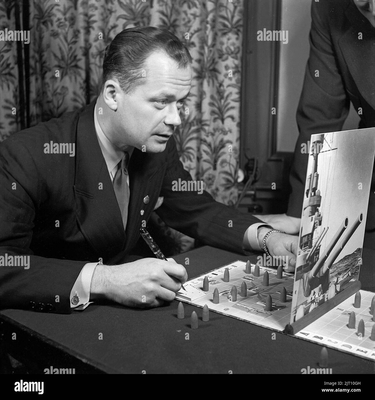 Spielen in der 1940s. Ein Mann spielt das Spiel Tak-tic, ähnlich wie das Spiel sinkende Schiff. Das Ziel ist zu erraten, wo das Schiff der Gegenmacht steht, und dann weiter zu raten, bis das Schiff versenkt wird. Schweden 1942 Kristoffersson B58-3 Stockfoto