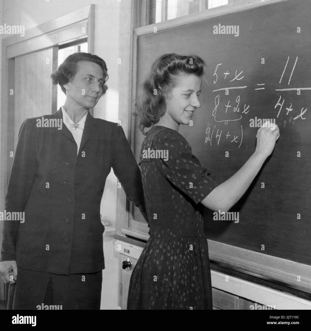Schule in der 1940s. Ein Lehrer vor dem Klassenzimmer an der schwarzen Tafel mit einem der Schüler, der eine mathematische Berechnung löst. Die Lehrerin ist Frau Aina Erlanger, Frau des schwedischen Premierministers Tage Erlanger. Schweden 1946 Stockfoto