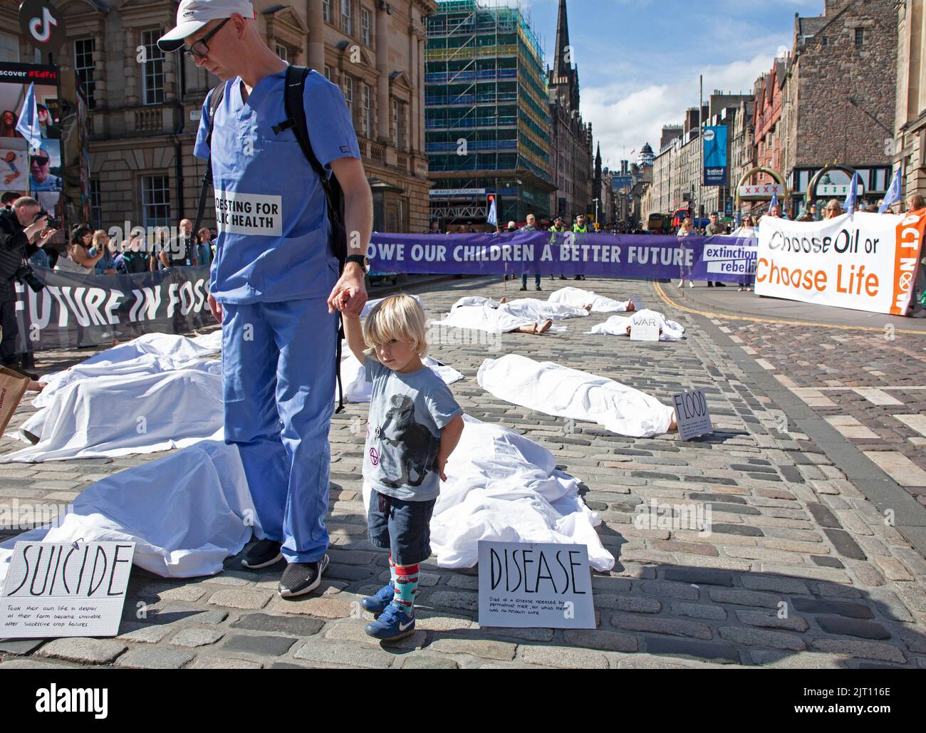 Royal Mile, Edinburgh, Schottland, Großbritannien. 27.. August 2022. Die Mitglieder der Edinburgher Extinction Rebellion protestieren in einem „Einfall“-Protest gegen die anhaltende Klimakrise, indem sie vor der St Giles Cathedral mit weißen Blättern bedeckt liegen, neben Plakaten, die die Ursachen von klimabedingten Todesfällen aufzeigen. Quelle: Arch White/alamy Live News Stockfoto