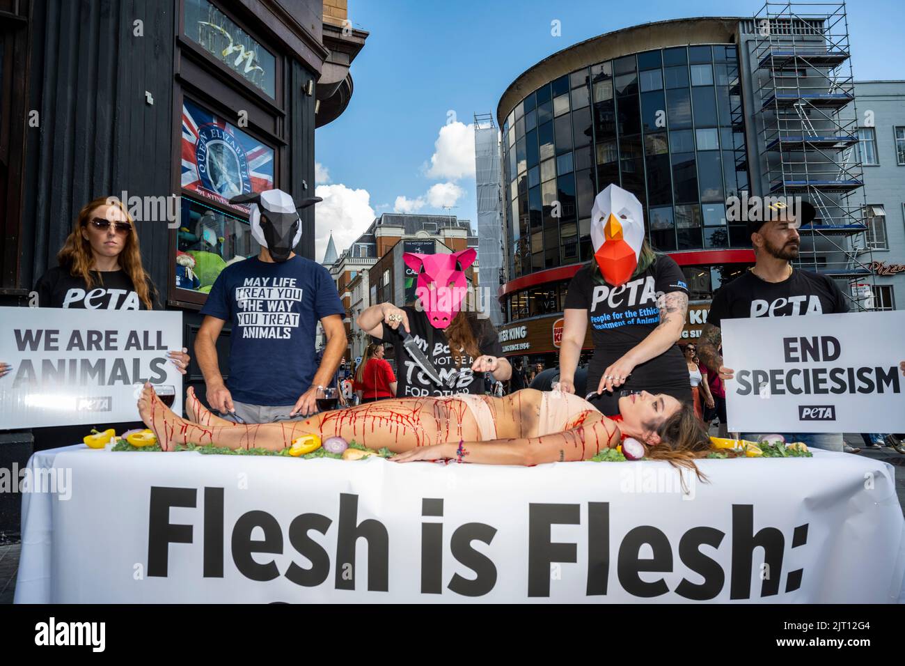 London, Großbritannien. 27. August 2022. Als Tiere gekleidete Demonstranten „speisen“ auf einem „blutverschmierten“ Menschen auf dem Leicester Square, um den „Welttag für das Ende des Speziesismus“ zu begehen. Das „Lunch-in“ ist Teil der Bemühungen von PETA (People for the Ethical Treatment of Animals), Speziesismus in Frage zu stellen und die Rechte der Tiere zu schützen. Kredit: Stephen Chung / EMPICS / Alamy Live Nachrichten Stockfoto