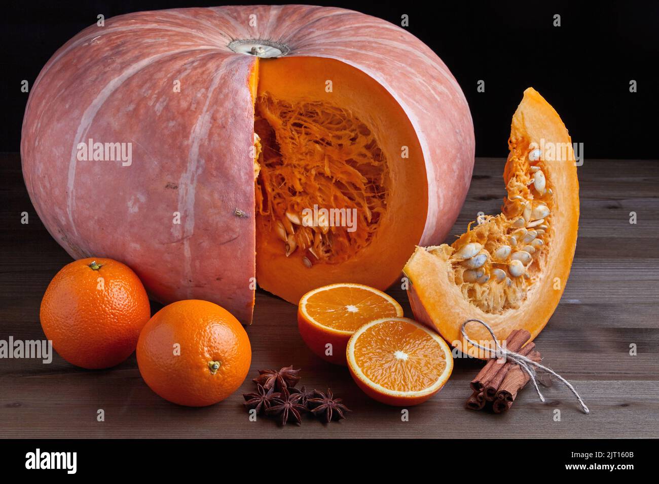 Frischer Bio-Kürbis, Orangenhälften und Zimtstangen auf dunklem Grund Stockfoto