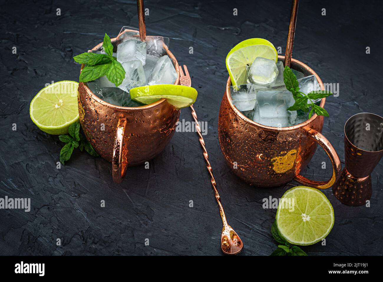 Eisiger kalter Moskauer Mule-Cocktail in einem Kupferbecher mit Ingwerbier, Wodka, Limette und Minze. Grauer Hintergrund. Stockfoto