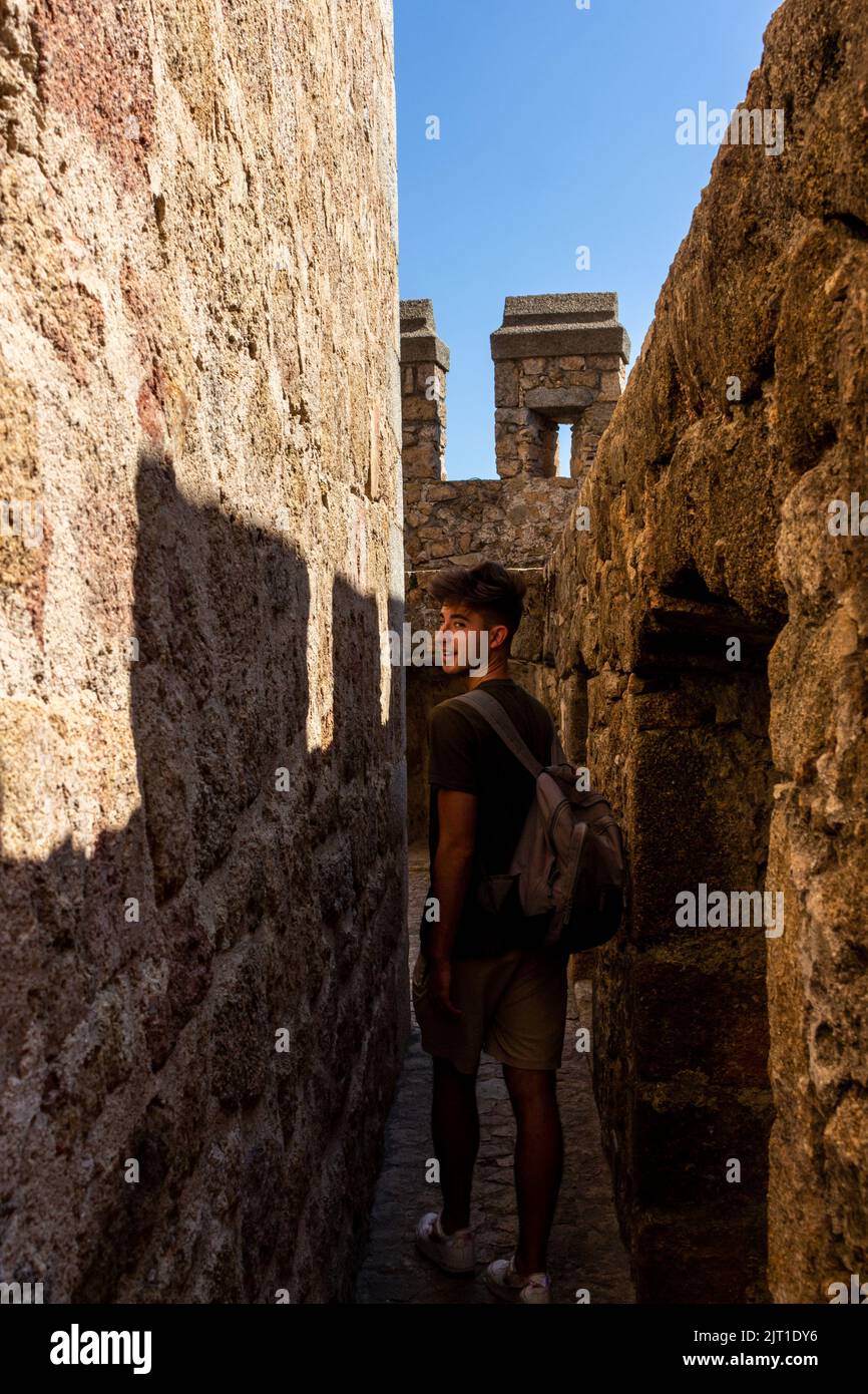 Ein hübscher Mann, der eine uralte Burg besucht und einen Rucksack trägt Stockfoto