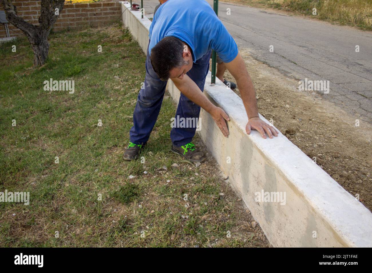 Bild eines Bauarbeiters, der die Glättung einer Betonwand eines Zauns überprüft. Do-it-yourself und Bauarbeiten Stockfoto