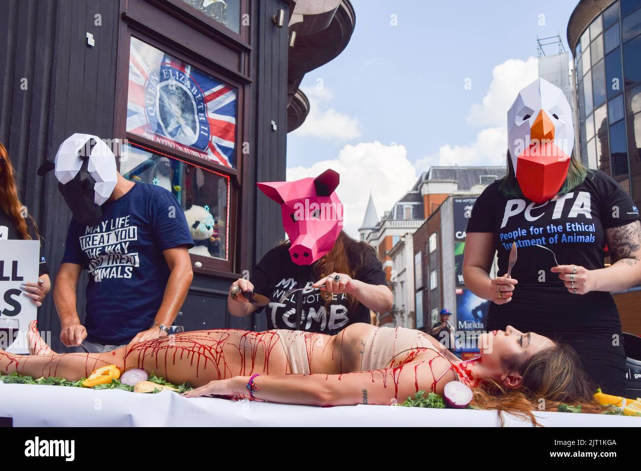 London, Großbritannien. 27. August 2022. PETA-Aktivisten (People for the Ethical Treatment of Animals), die Tiermasken tragen, "dinen" auf einen Aktivisten, der während des Protestes auf dem Leicester Square mit gefälschtem Blut bedeckt war. Die Aktion, die den Welttag für das Ende des Speziesismus markiert, ist Teil der laufenden Kampagne von PETA zur Beendigung des Speziesismus und zur Ermutigung der Menschen, vegan zu gehen. Kredit: SOPA Images Limited/Alamy Live Nachrichten Stockfoto
