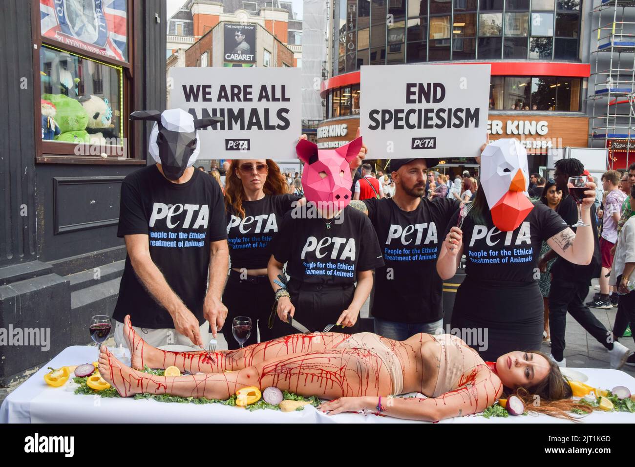 London, Großbritannien. 27. August 2022. PETA-Aktivisten (People for the Ethical Treatment of Animals), die Tiermasken tragen, "dinen" auf einen Aktivisten, der während des Protestes auf dem Leicester Square mit gefälschtem Blut bedeckt war. Die Aktion, die den Welttag für das Ende des Speziesismus markiert, ist Teil der laufenden Kampagne von PETA zur Beendigung des Speziesismus und zur Ermutigung der Menschen, vegan zu gehen. Kredit: SOPA Images Limited/Alamy Live Nachrichten Stockfoto