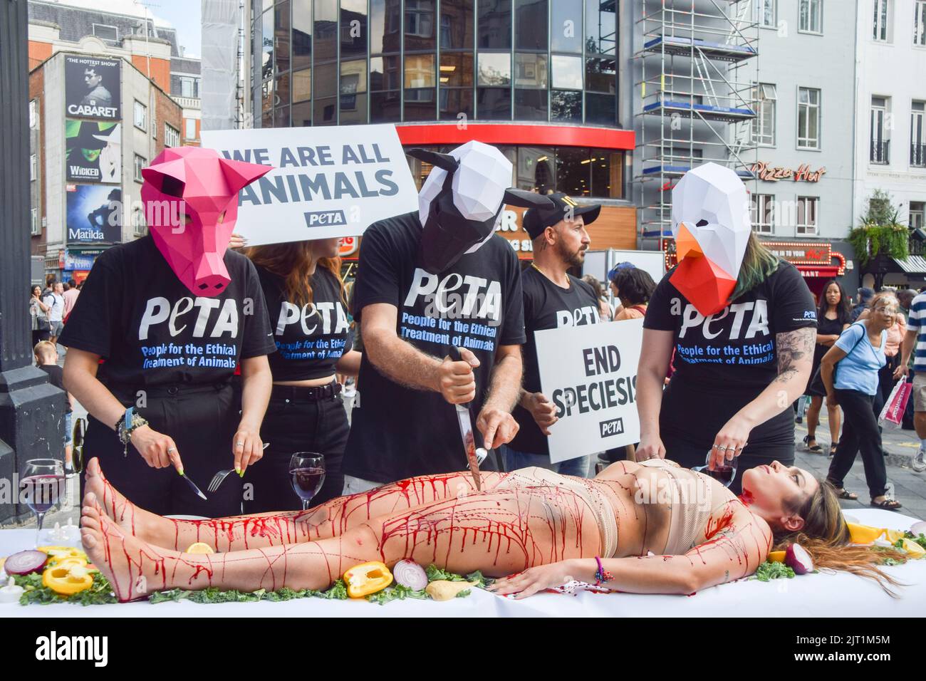 London, Großbritannien. 27. August 2022. PETA-Aktivisten (People for the Ethical Treatment of Animals), die Tiermasken tragen, "dinen" auf einen Aktivisten, der während des Protestes auf dem Leicester Square mit gefälschtem Blut bedeckt war. Die Aktion, die den Welttag für das Ende des Speziesismus markiert, ist Teil der laufenden Kampagne von PETA zur Beendigung des Speziesismus und zur Ermutigung der Menschen, vegan zu gehen. (Foto: Vuk Valcic/SOPA Images/Sipa USA) Quelle: SIPA USA/Alamy Live News Stockfoto