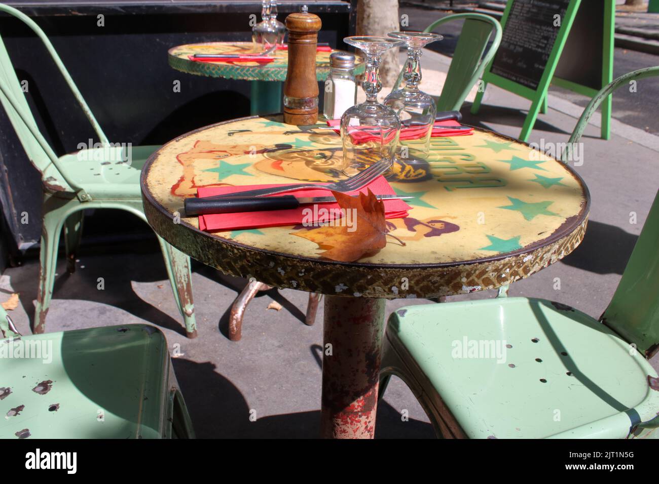 Abstrakter Blick auf einen grünen Tisch und Stühle vor einer typischen französischen Brasserie, die Touristen oder Einheimische in Paris erwartet. Stockfoto