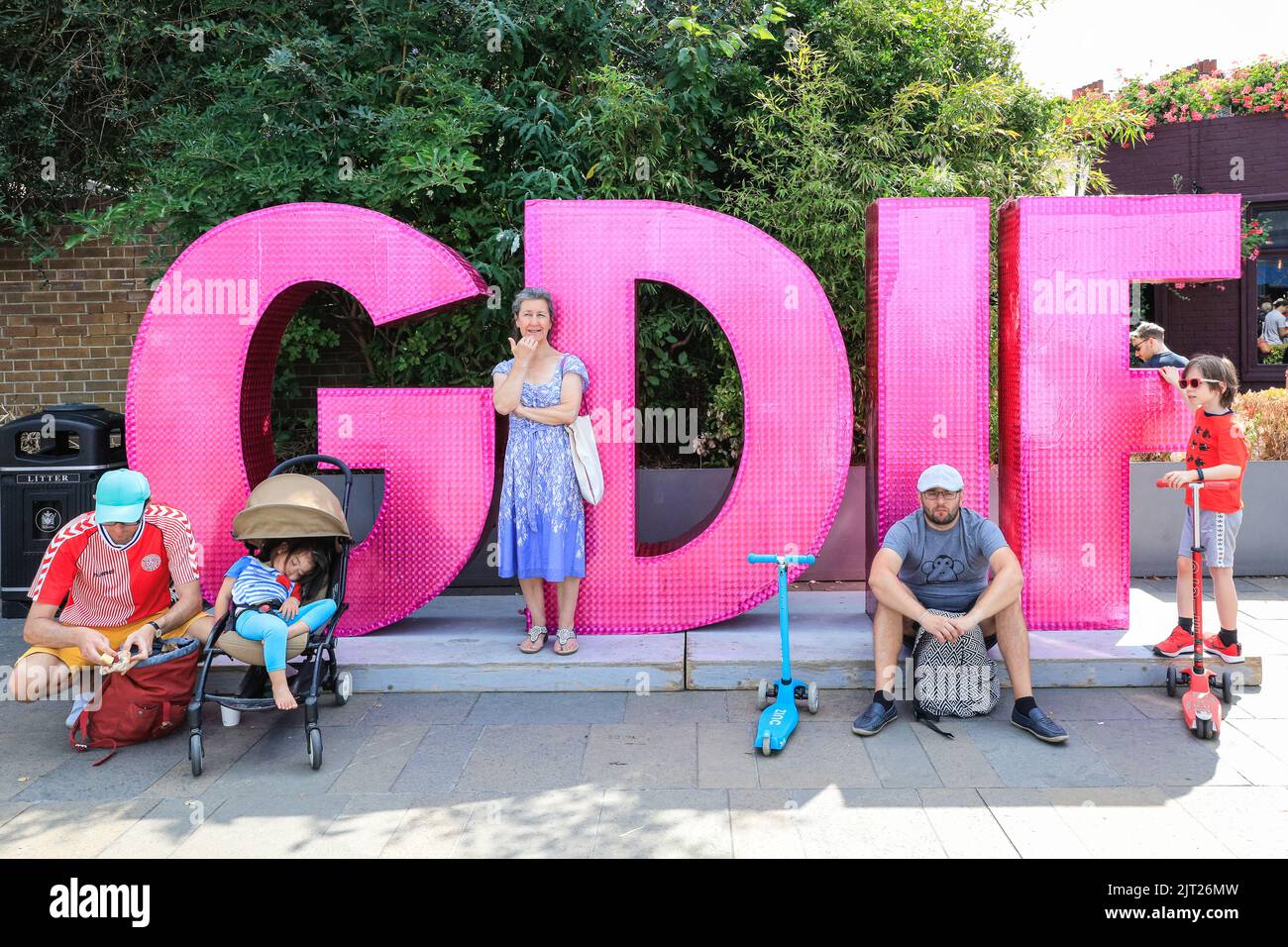 London, Großbritannien. 27. August 2022. Auf dem Logo des GDIF Greenwich and Docklands International Festival in den Cutty Sark Gardens in Greenwich, wo an diesem Wochenende einige der Aufführungen des großen, interaktiven und kostenlosen Festivals stattfinden, sitzen die Menschen und ruhen sich aus. Kredit: Imageplotter/Alamy Live Nachrichten Stockfoto