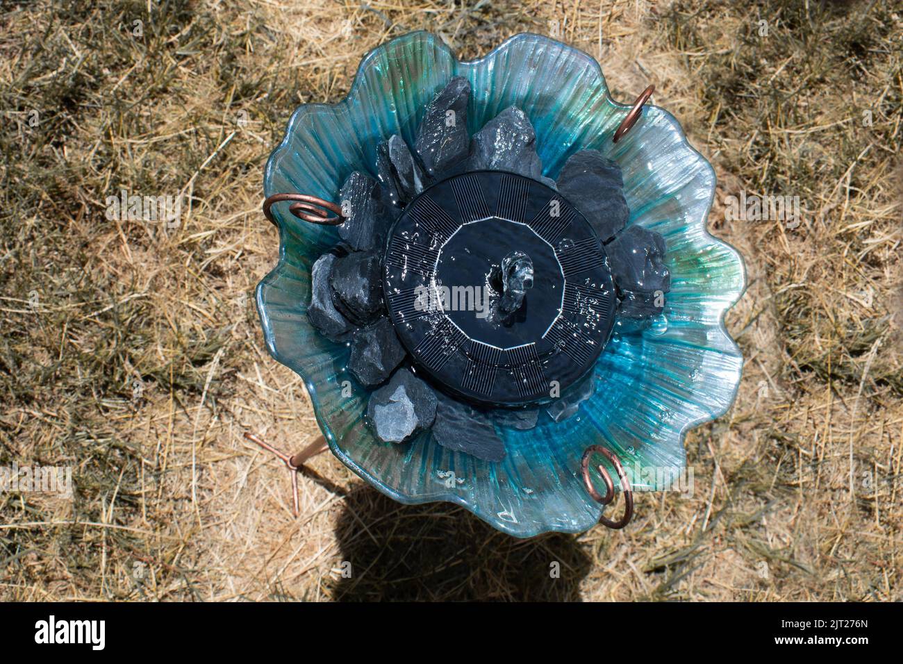 Blaues und grünes Vogelbad mit solarbetriebener Fontäne und Steinen für Kolibris Stockfoto