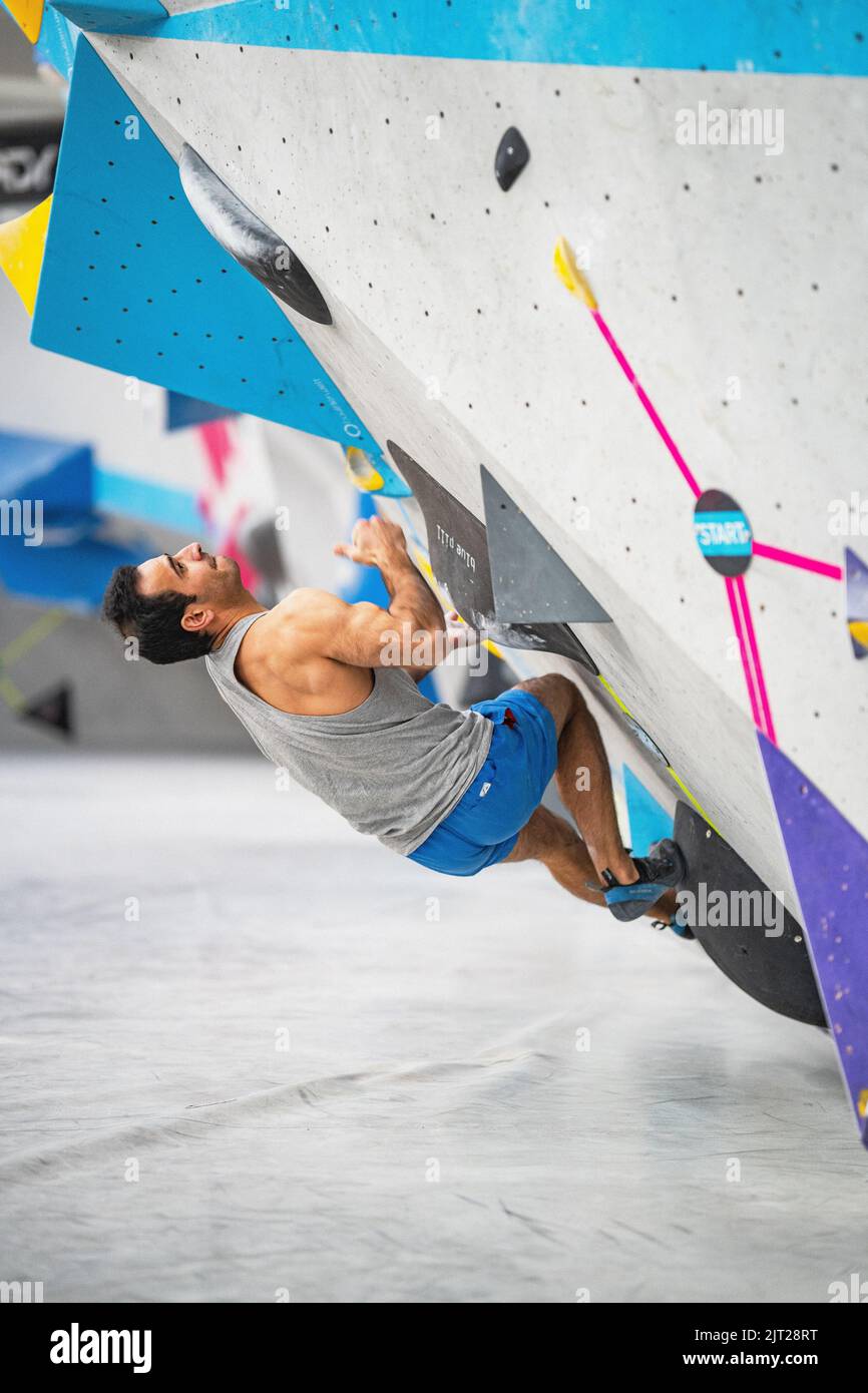 Ein starker Mann klettert an der Wand in der Kletterhalle Stockfoto