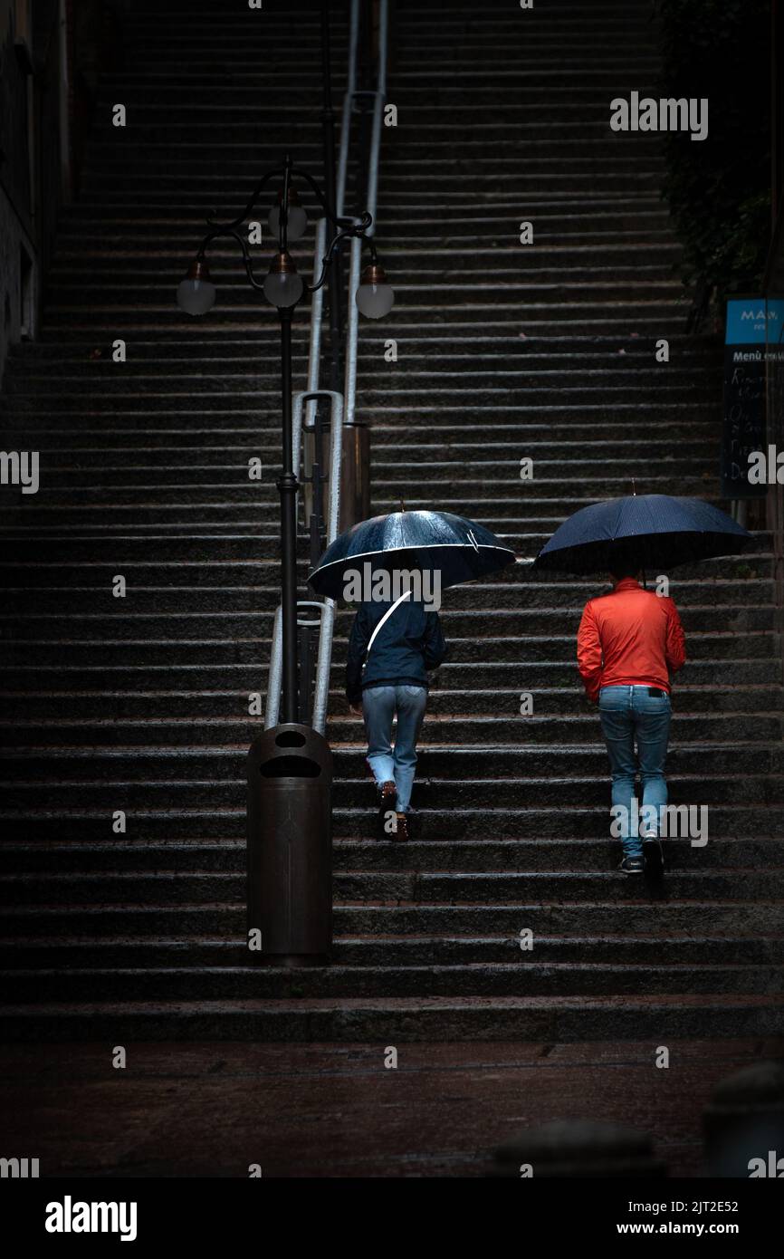 Eine dramatische Aufnahme von zwei Personen, die an einem regnerischen Tag die Treppe erklimmen Stockfoto