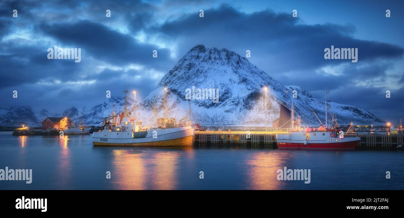 Fischerboote auf dem Meer, schneebedeckte felsige Berge, blauer Himmel Stockfoto