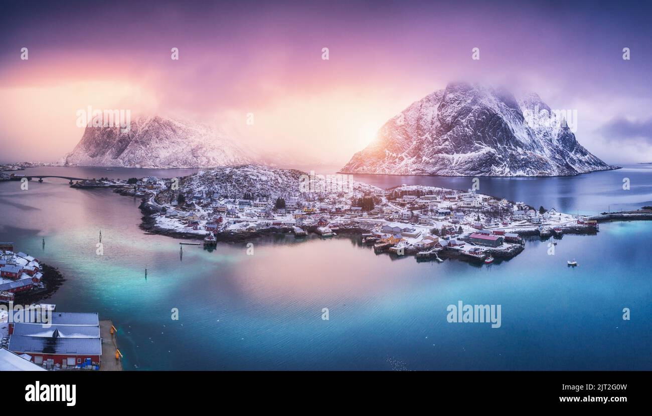 Luftaufnahme des Dorfes auf der Insel, blaues Meer, schneebedeckte Berge Stockfoto