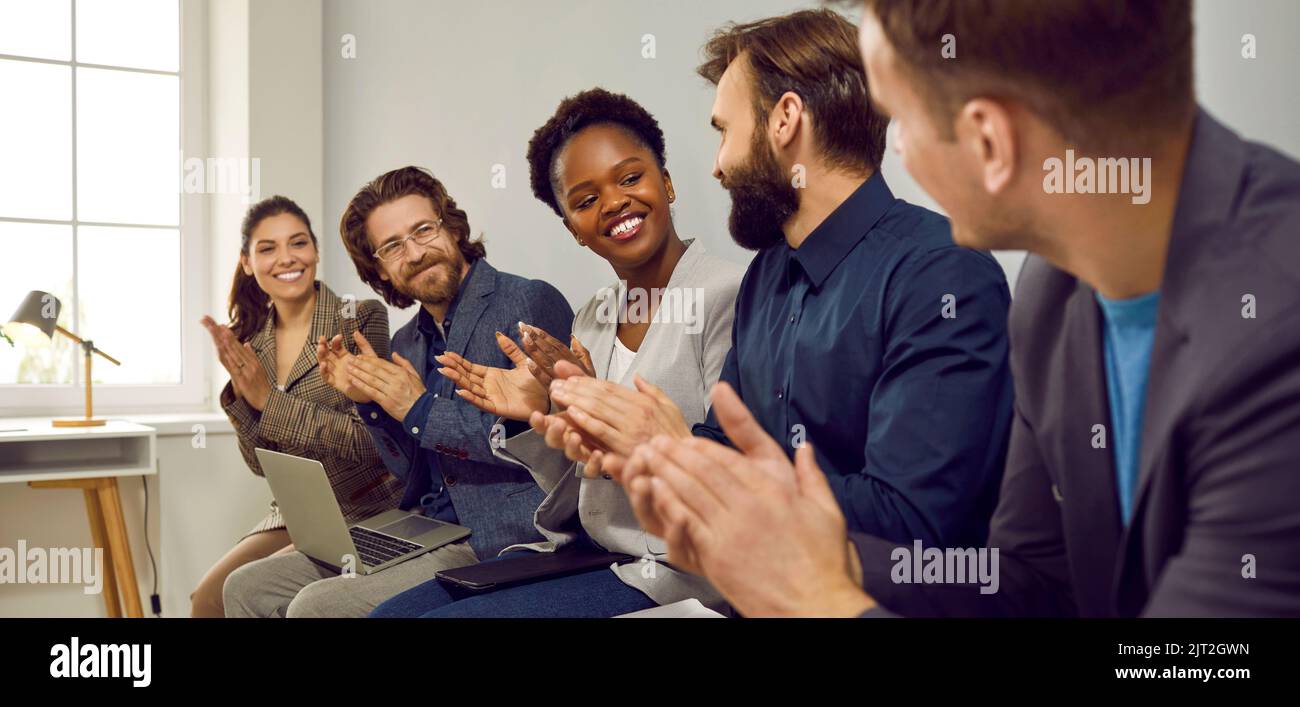 Glückliches Team, das dem Kollegen nach einer Geschäftspräsentation bei einem Arbeitsgespräch Anerkennung zeigt Stockfoto