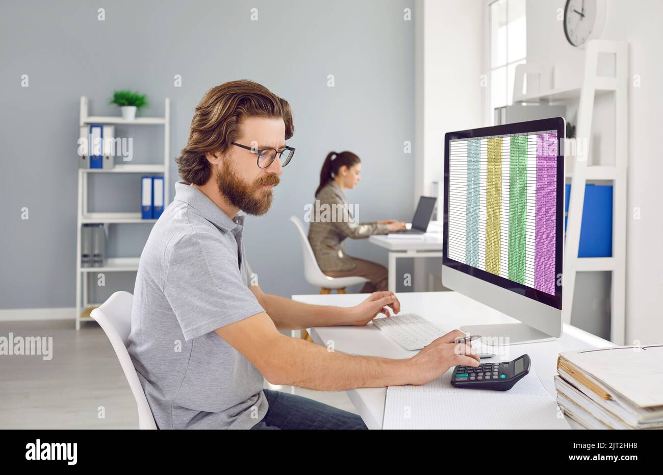 Der männliche Buchhalter verwendet den Rechner, um den Finanzbericht zu berechnen, der im Büro mit dem Computer arbeitet. Stockfoto